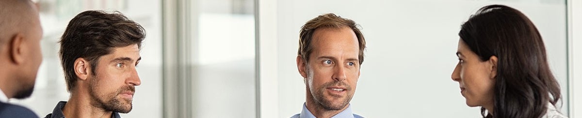 Businessman giving some new ideas about project to his partners in conference room. Mature leader discussing over new business plans in office with his employees. A group of businessmen and businesswoman talking during meeting.